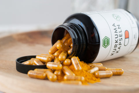 Bio Kurkumapulver Kapseln 180 Stück in PET-Dose ausgeschüttet auf Teller